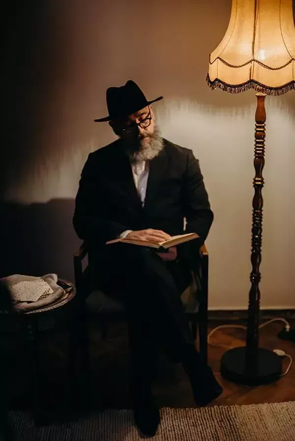 Gläubiger älterer Jude sitzt in einem Stuhl und liest ein heiliges Buch