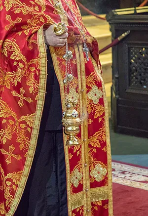 Ein Mann in einem rot-goldenen Gewand hält eine Kerze.